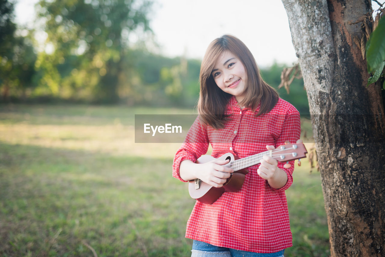 Smiling young woman standing on tree trunk