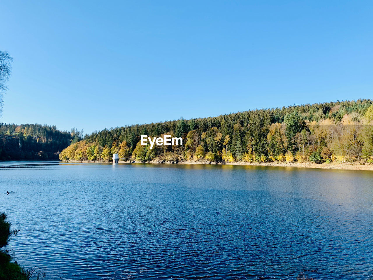 Scenic view of lake against clear blue sky