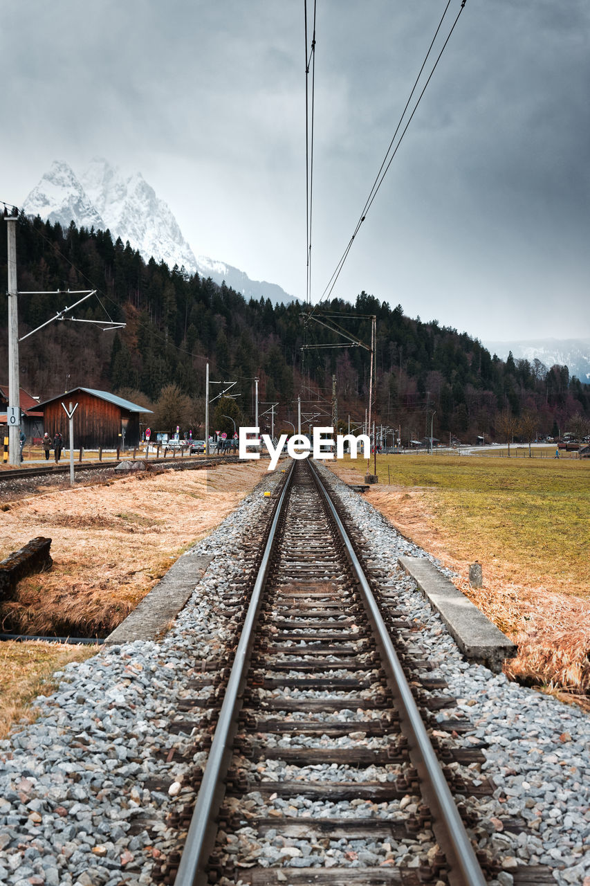 RAILROAD TRACK AMIDST TREES AGAINST SKY