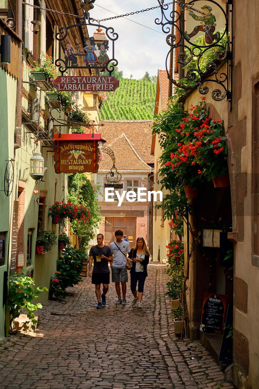 PEOPLE WALKING ON STREET AMIDST BUILDINGS IN CITY