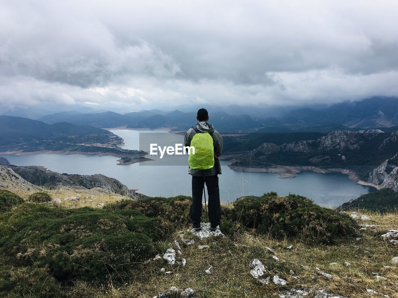 Man standing on a pick of the mountain against sky and views of a lake