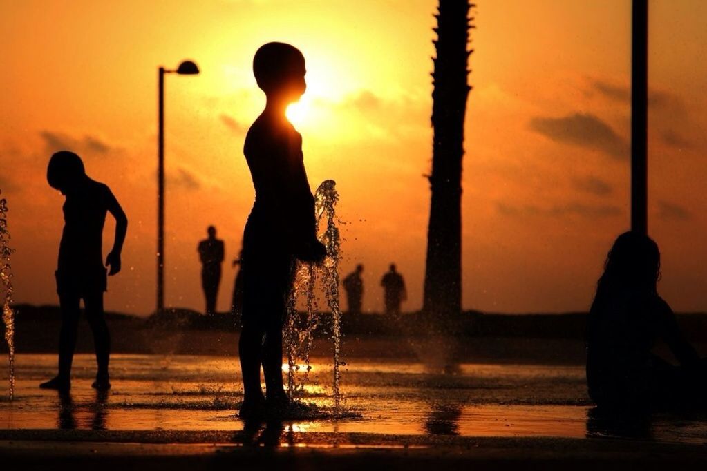 Silhouette children playing at water fountain