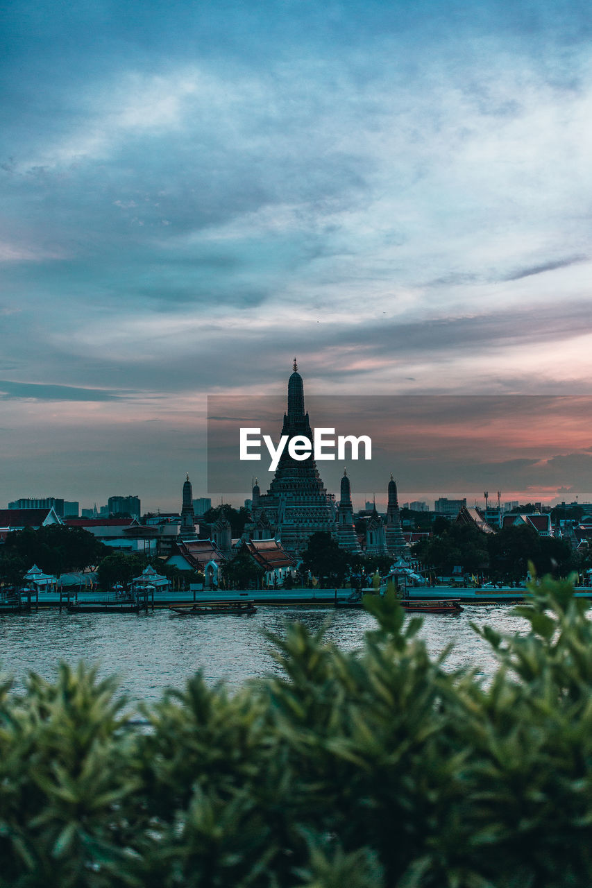 Temple by river during sunset in city