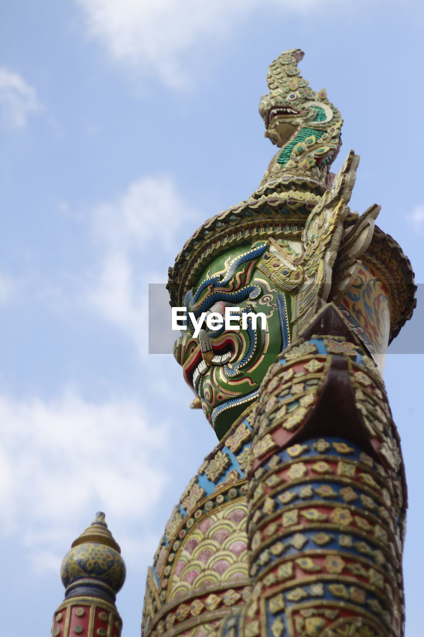 Low angle view of human sculpture against sky