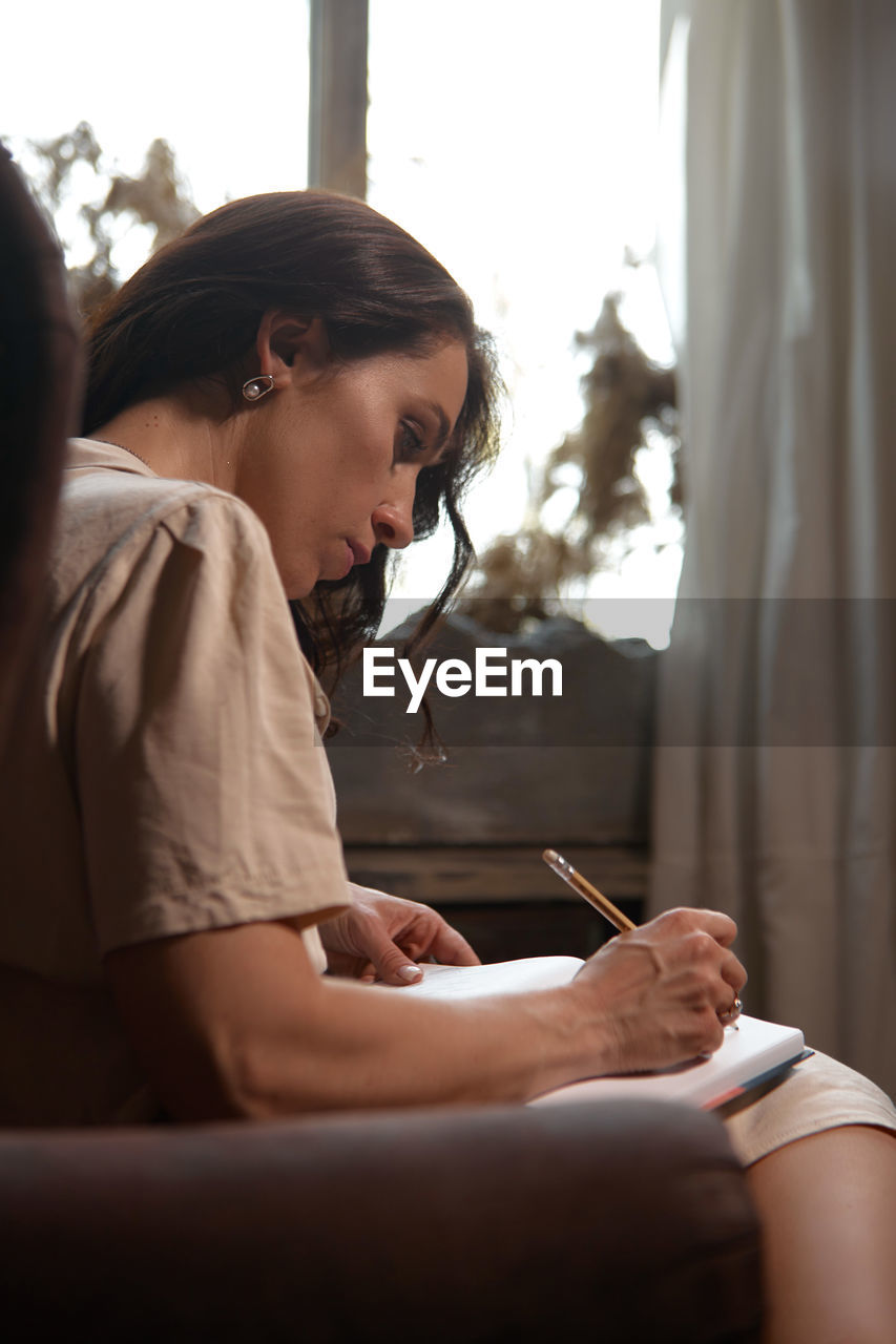 Woman writing in book at home