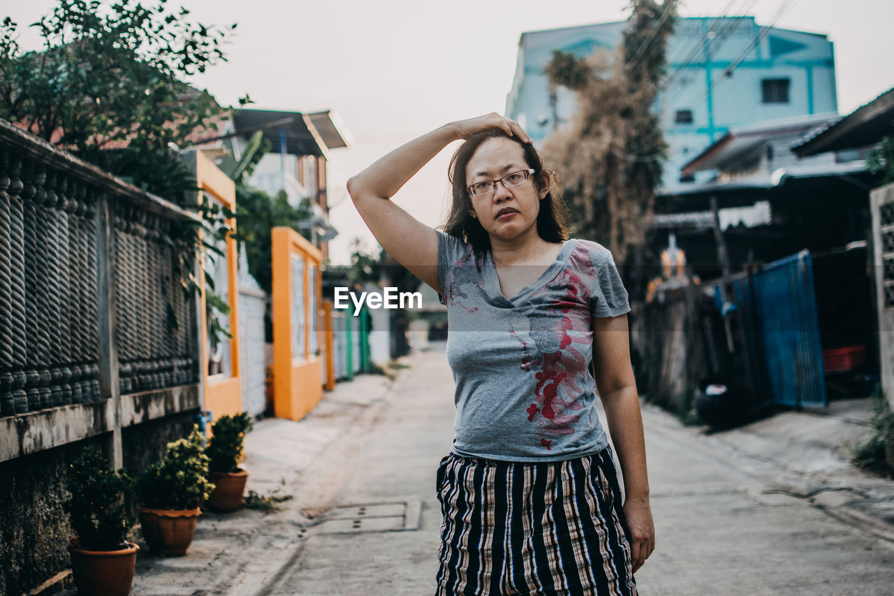 Young woman standing on street against buildings in city