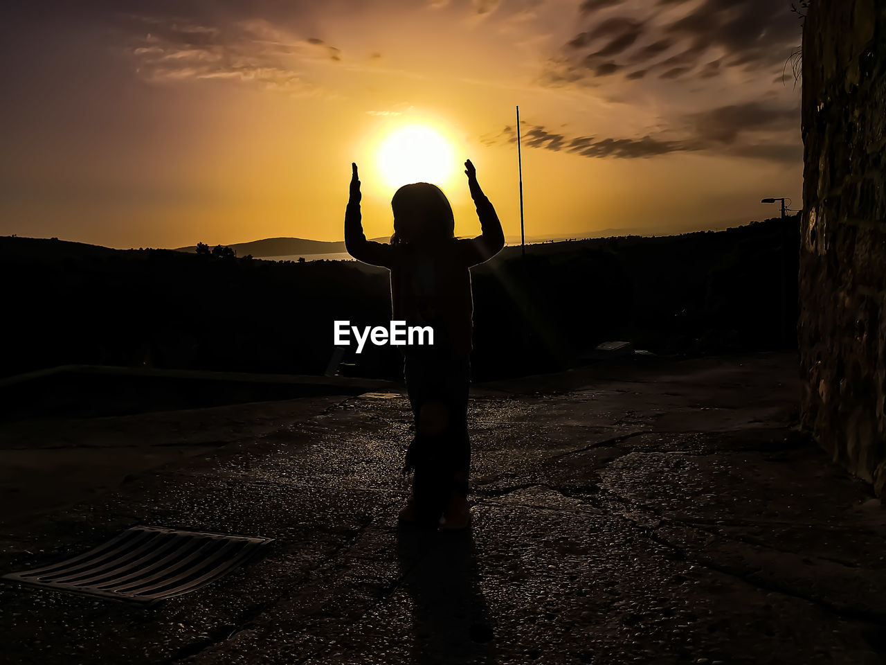 Silhouette girl standing on street during sunset