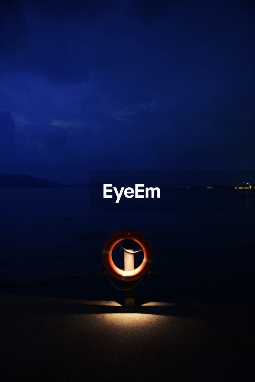 VIEW OF ILLUMINATED BEACH AGAINST SKY AT NIGHT