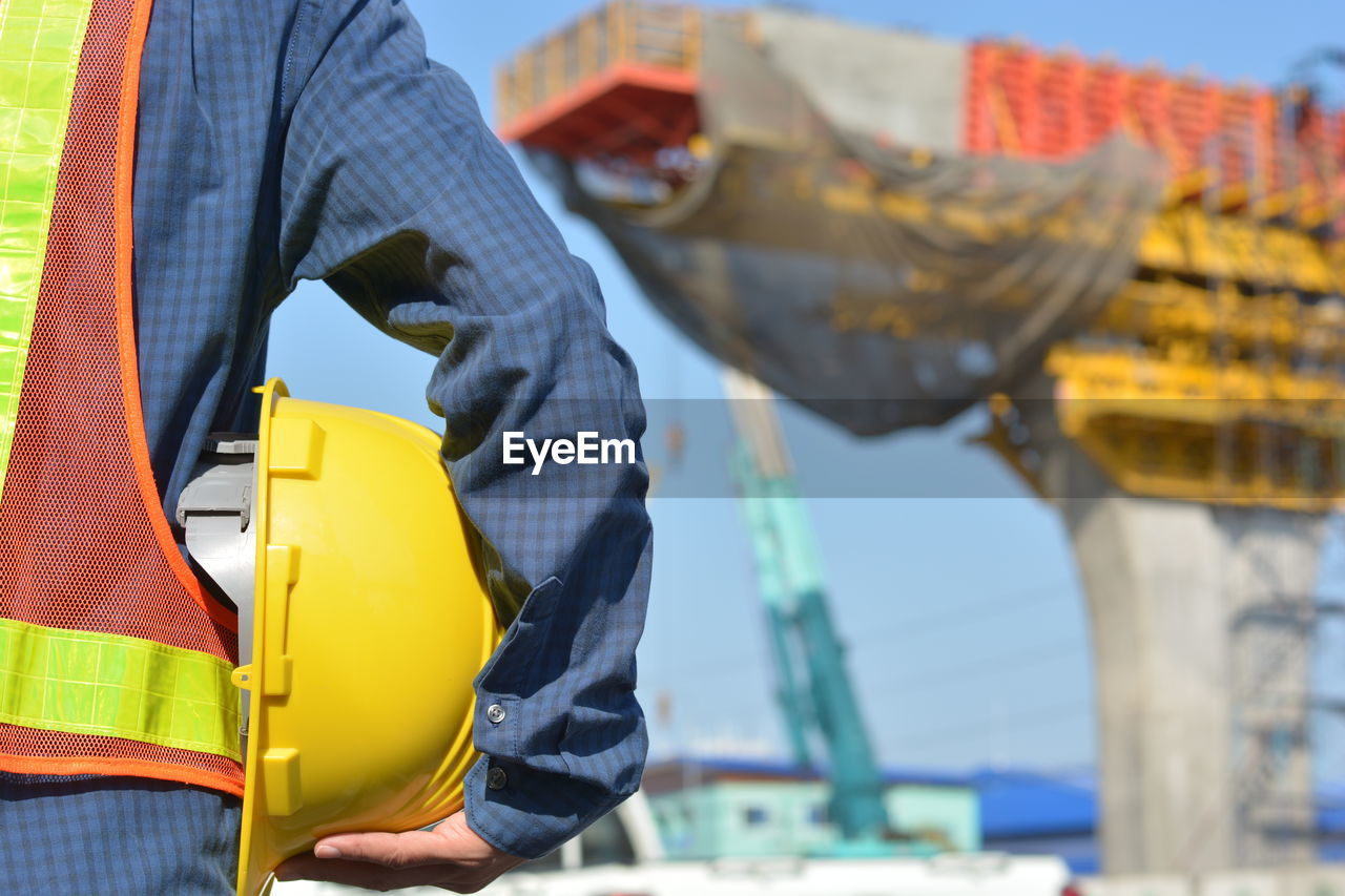 Midsection of man holding hardhat