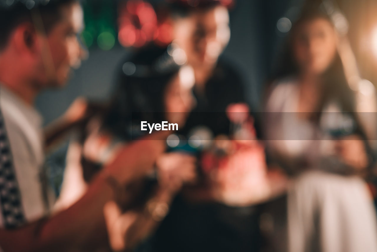 Defocused image of friends enjoying birthday party at home