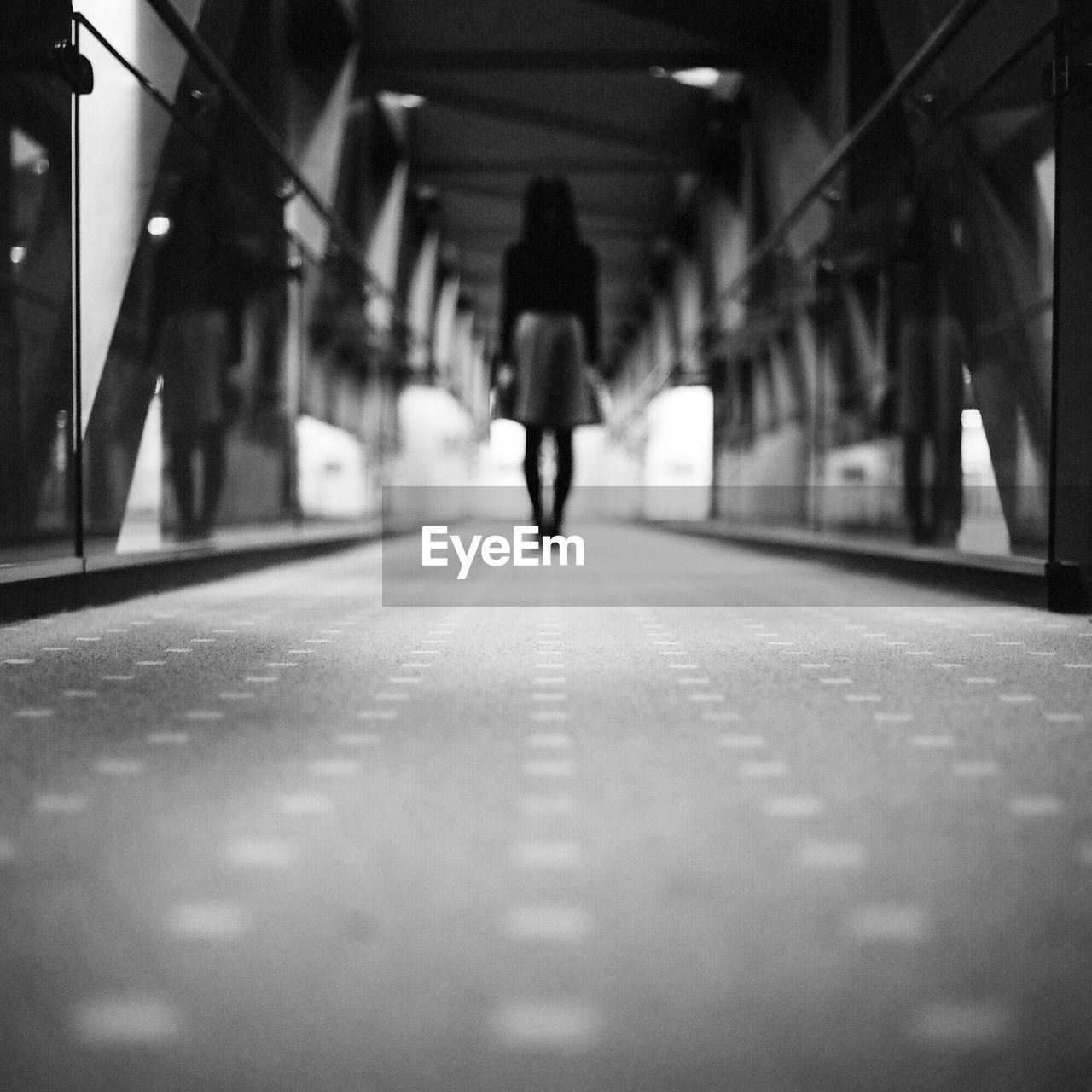 Rear view of woman standing on covered walkway