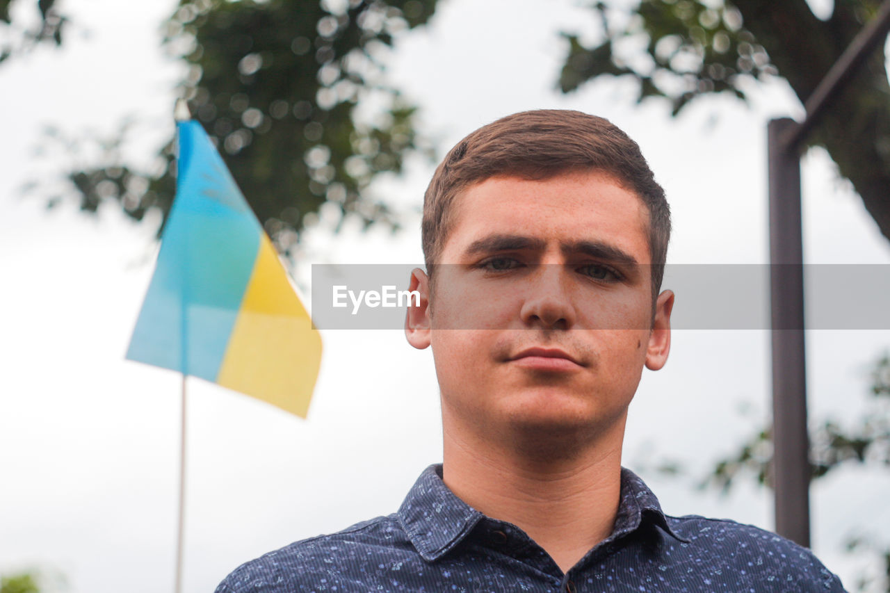 Ukrainian man. young serious man holding ukrainian flag. no war. support for ukraine. patriotic 