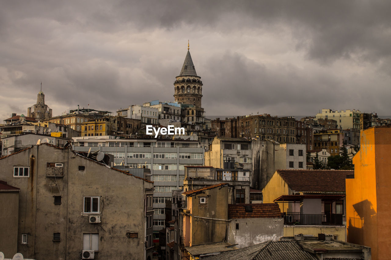 Buildings in city against cloudy sky