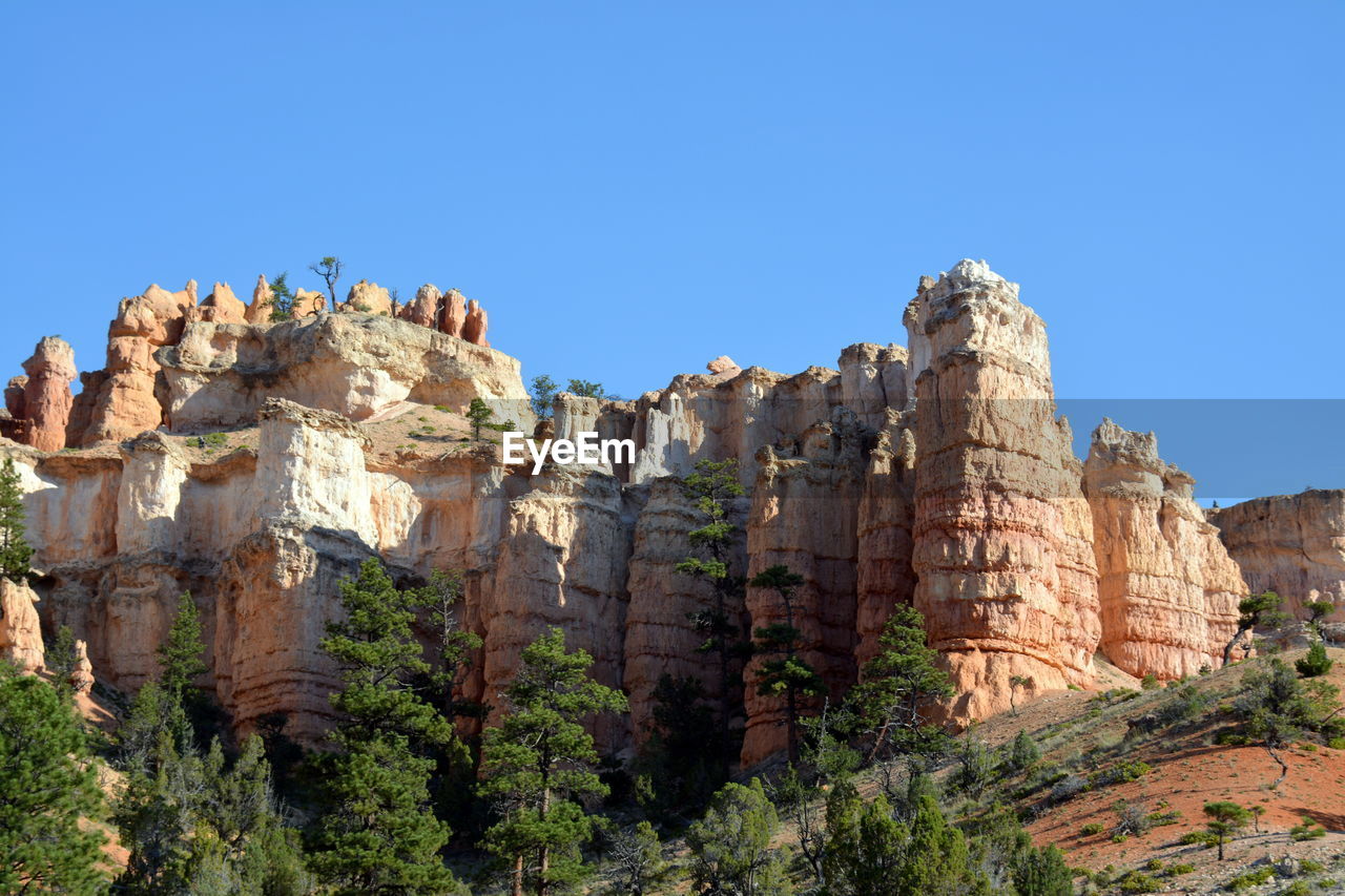 Low angle view of rock formation against clear blue sky