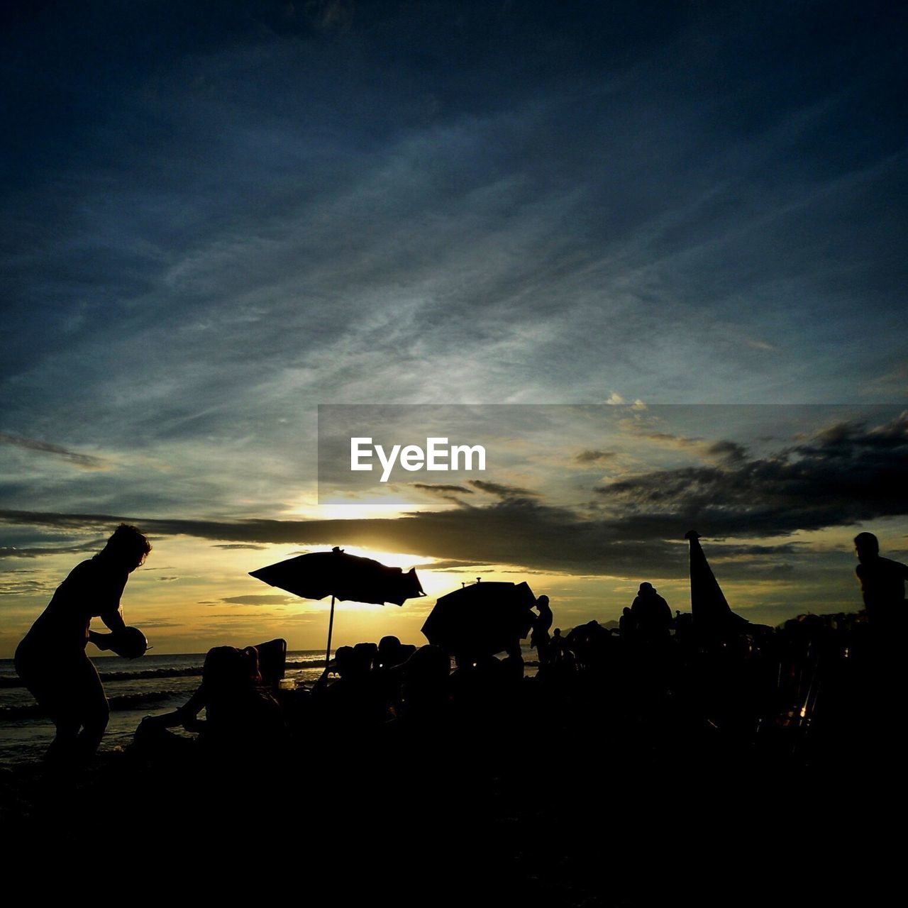 People relaxing on beach at sunset