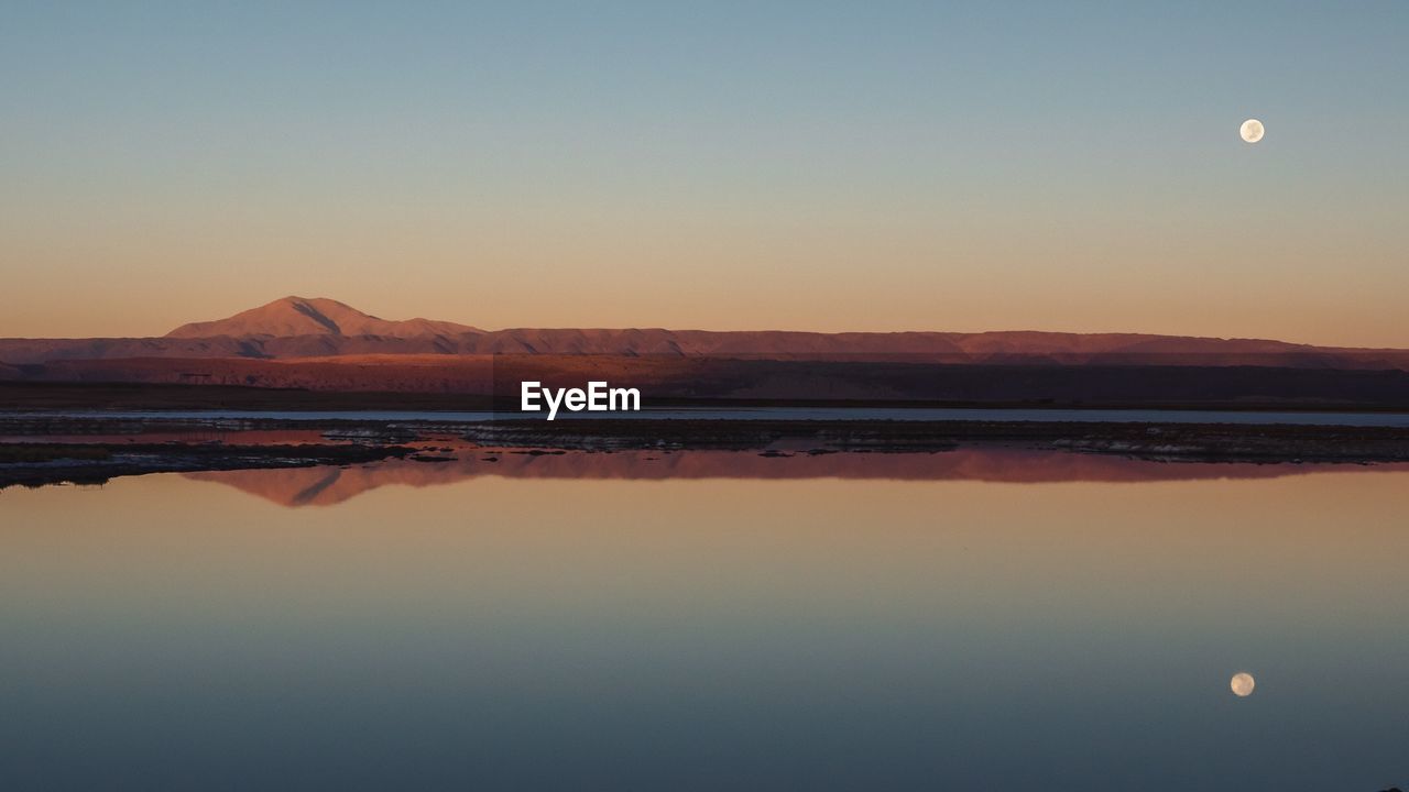 Scenic view of lake against clear sky during sunset