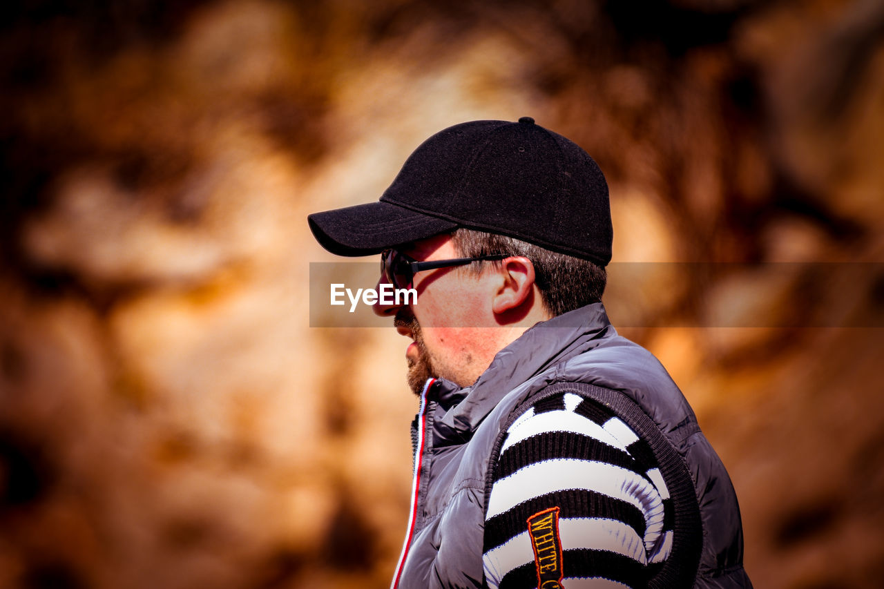 PORTRAIT OF YOUNG MAN LOOKING AWAY OUTDOORS