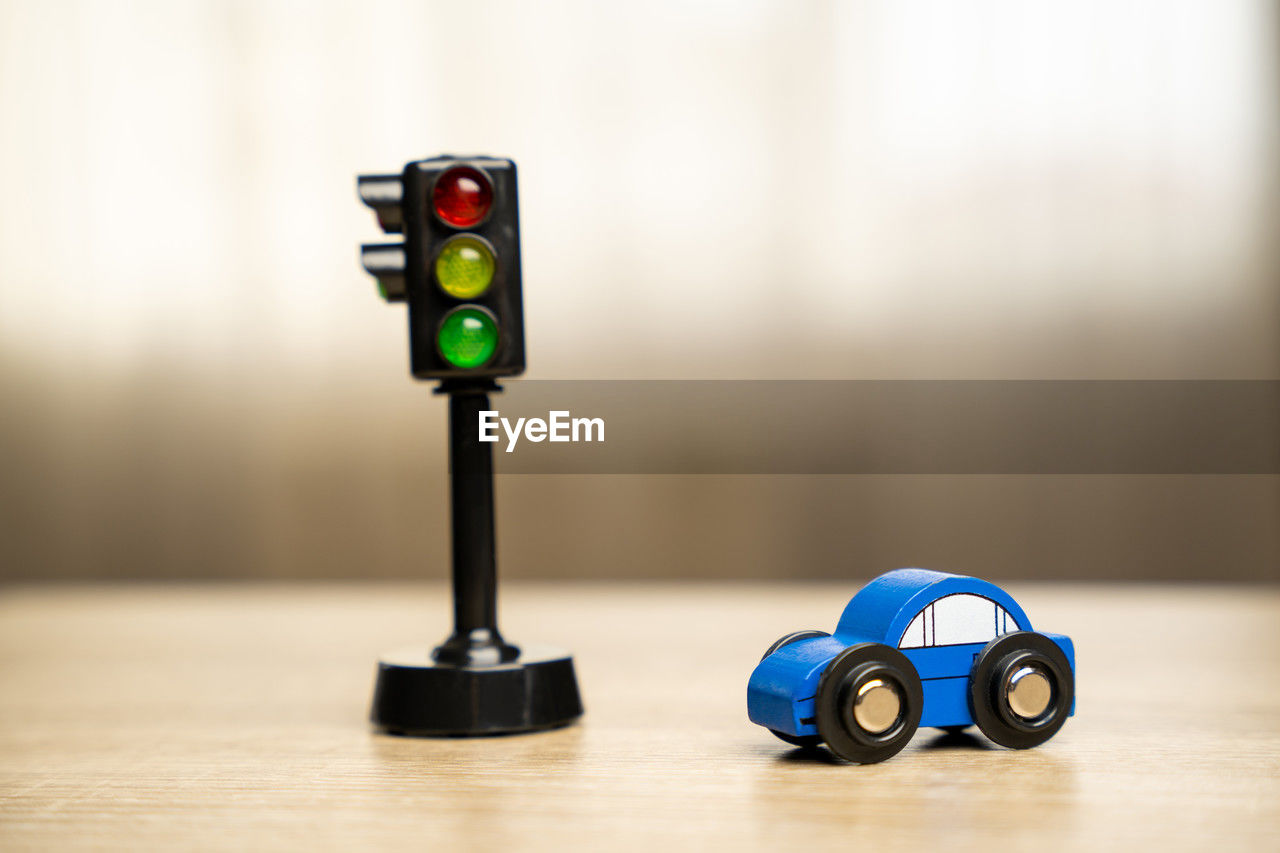 A toy blue car near a traffic light on the table
