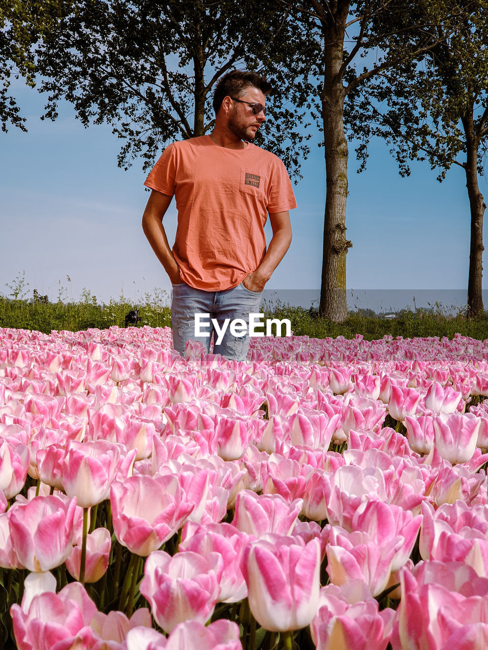 FULL LENGTH OF MAN STANDING BY PINK FLOWER