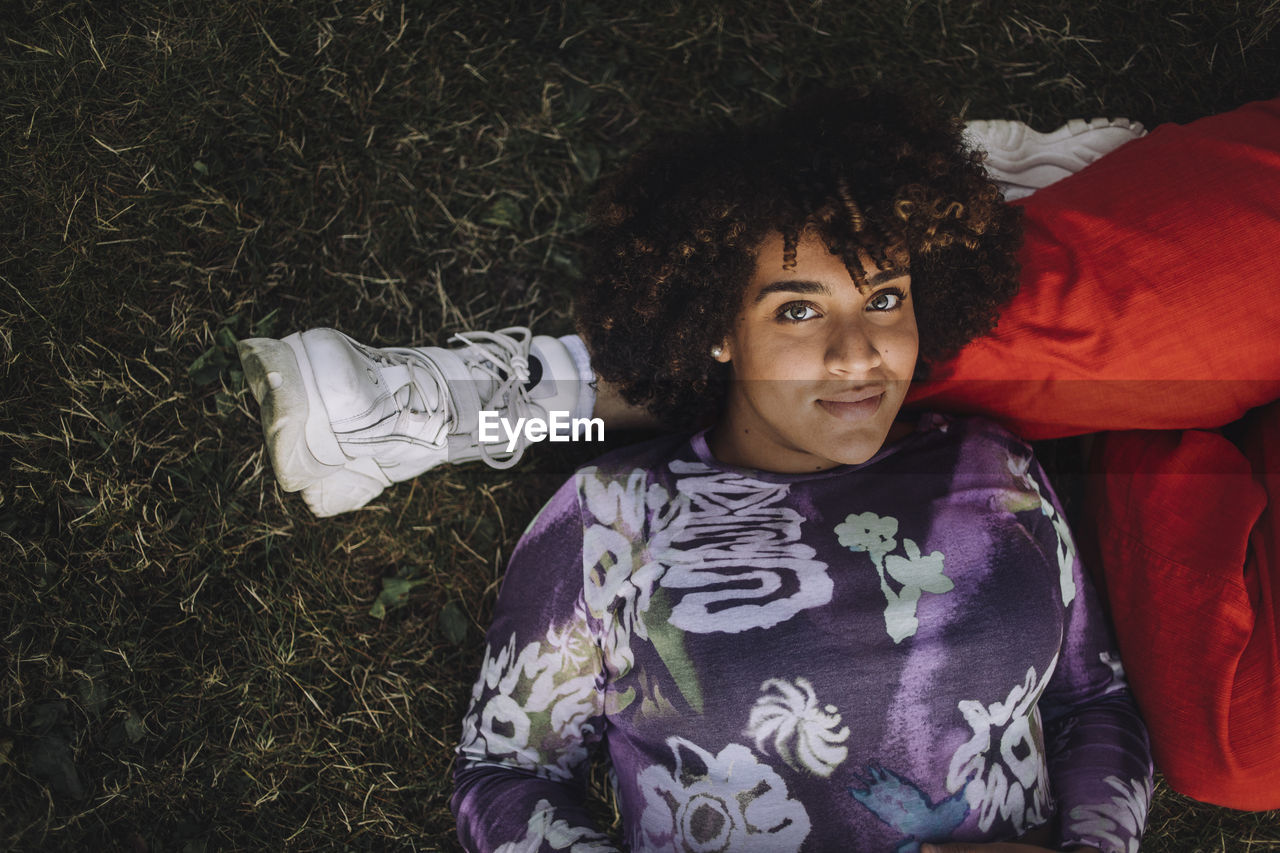 Portrait of smiling transgender woman lying on non-binary friend's leg