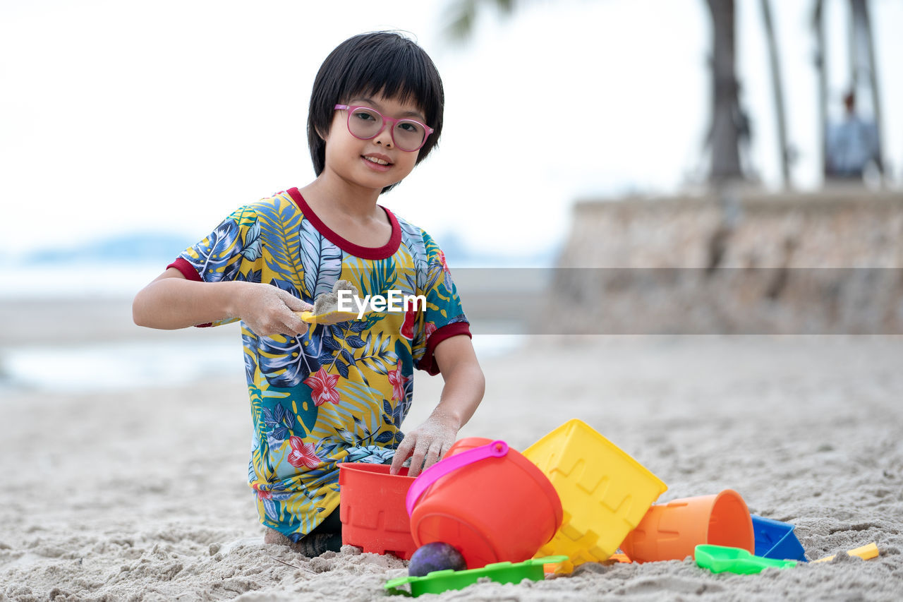 Portrait of smiling girl with toy playing on sandy beach