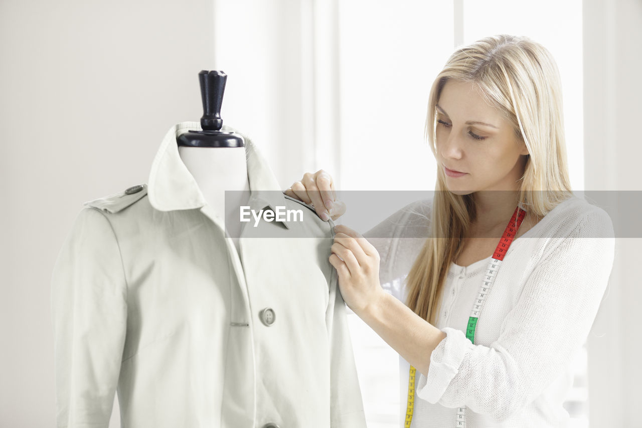 Woman preparing coat on mannequin