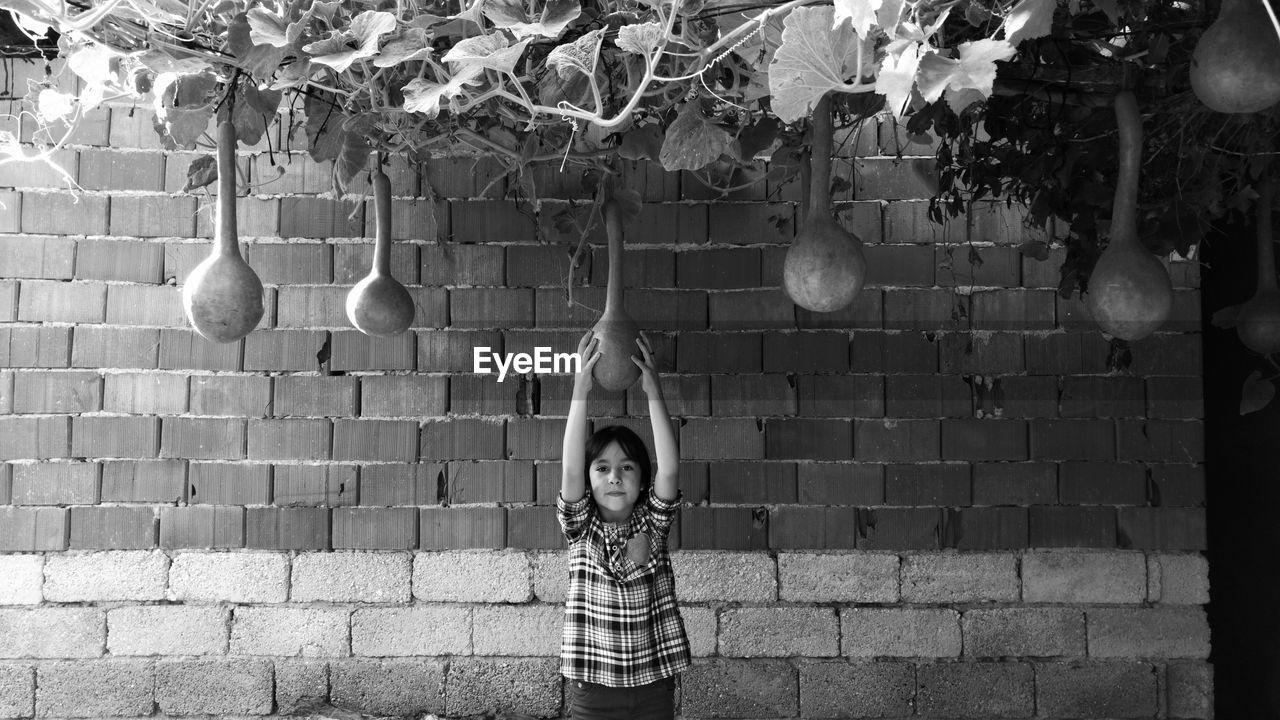 Girl holding vegetable hanging on plant