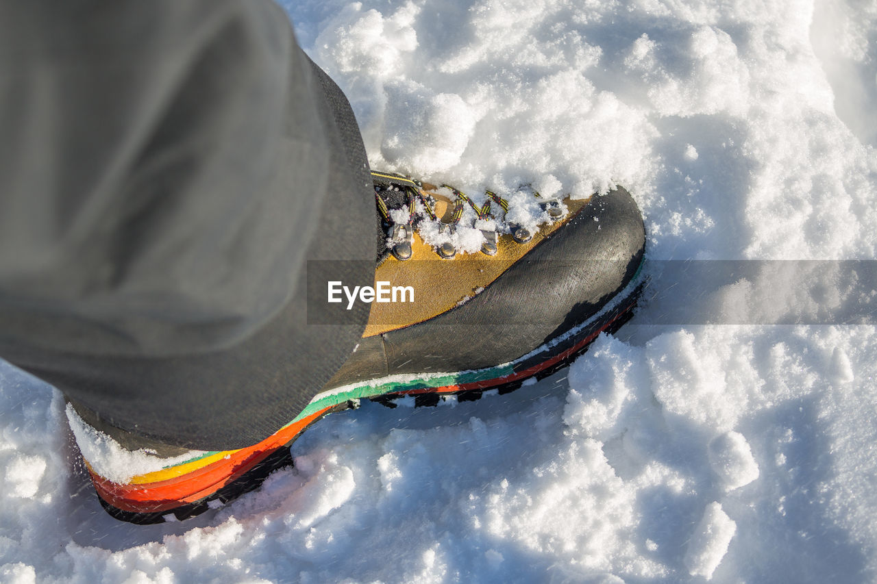 Low section of person wearing hiking boots on snow