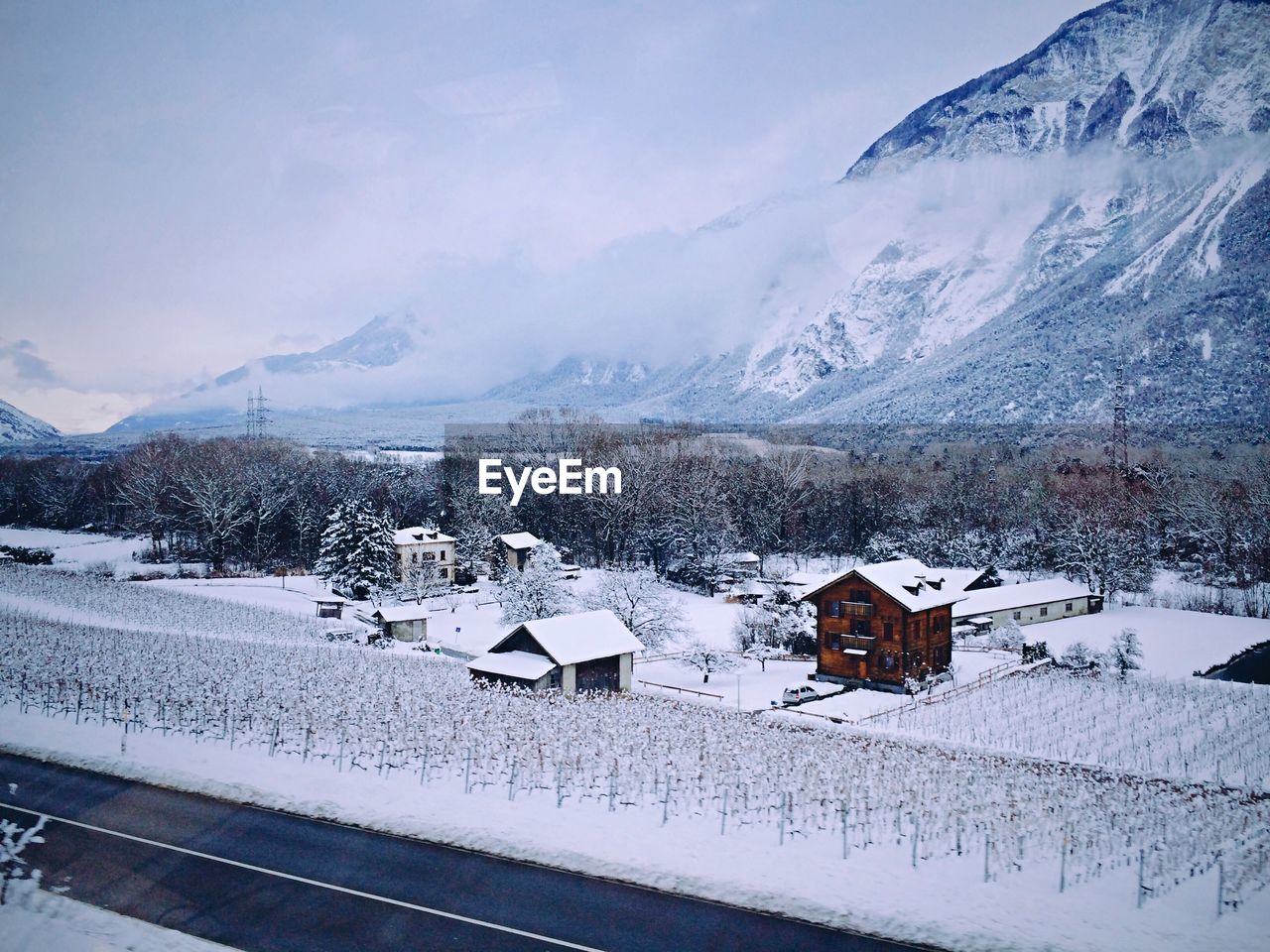 Snow covered houses by building against sky