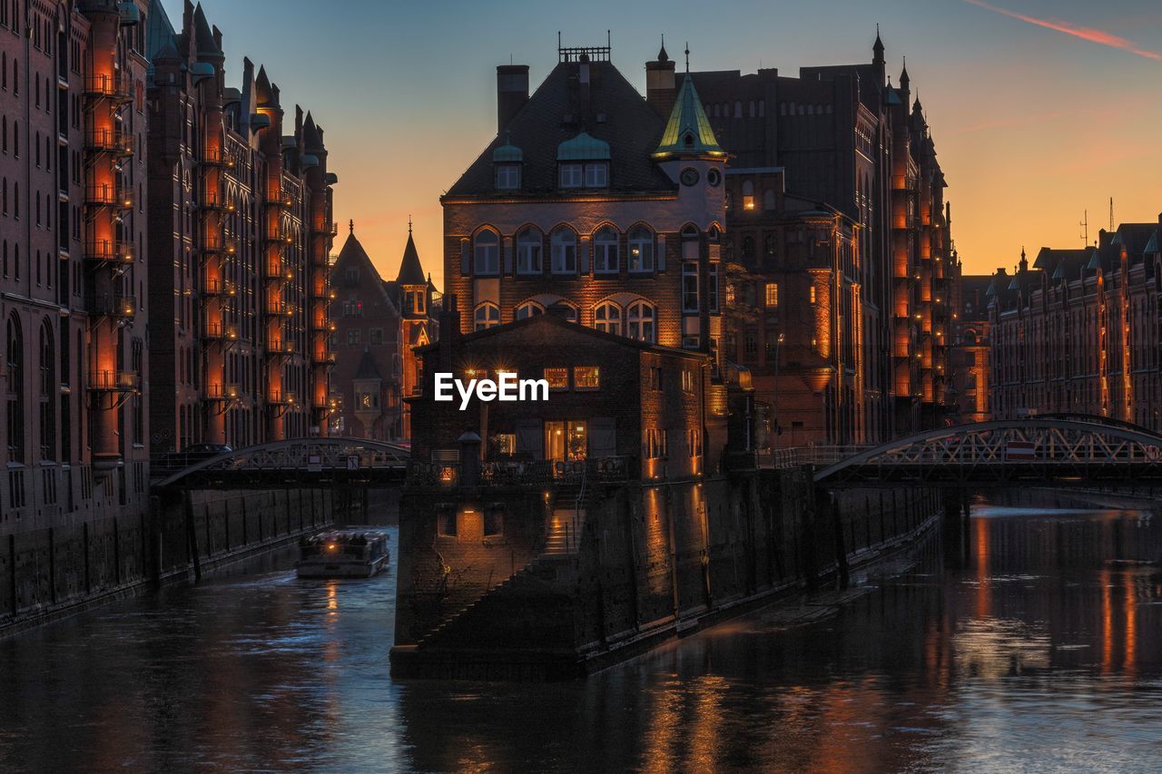 Canal passing through city buildings at sunset