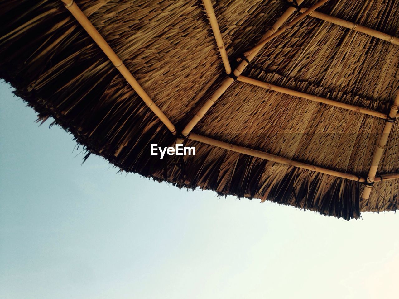 Low angle view of thatched roof against sky during sunny day