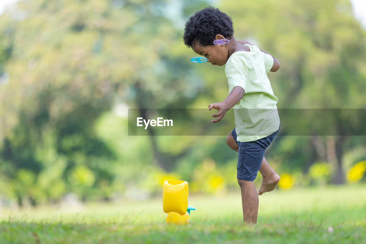 side view of boy playing with straw in park