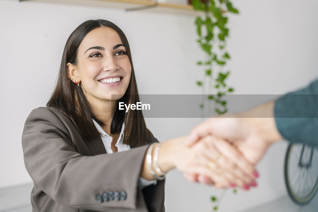 Happy recruiter shaking hand with candidate in office