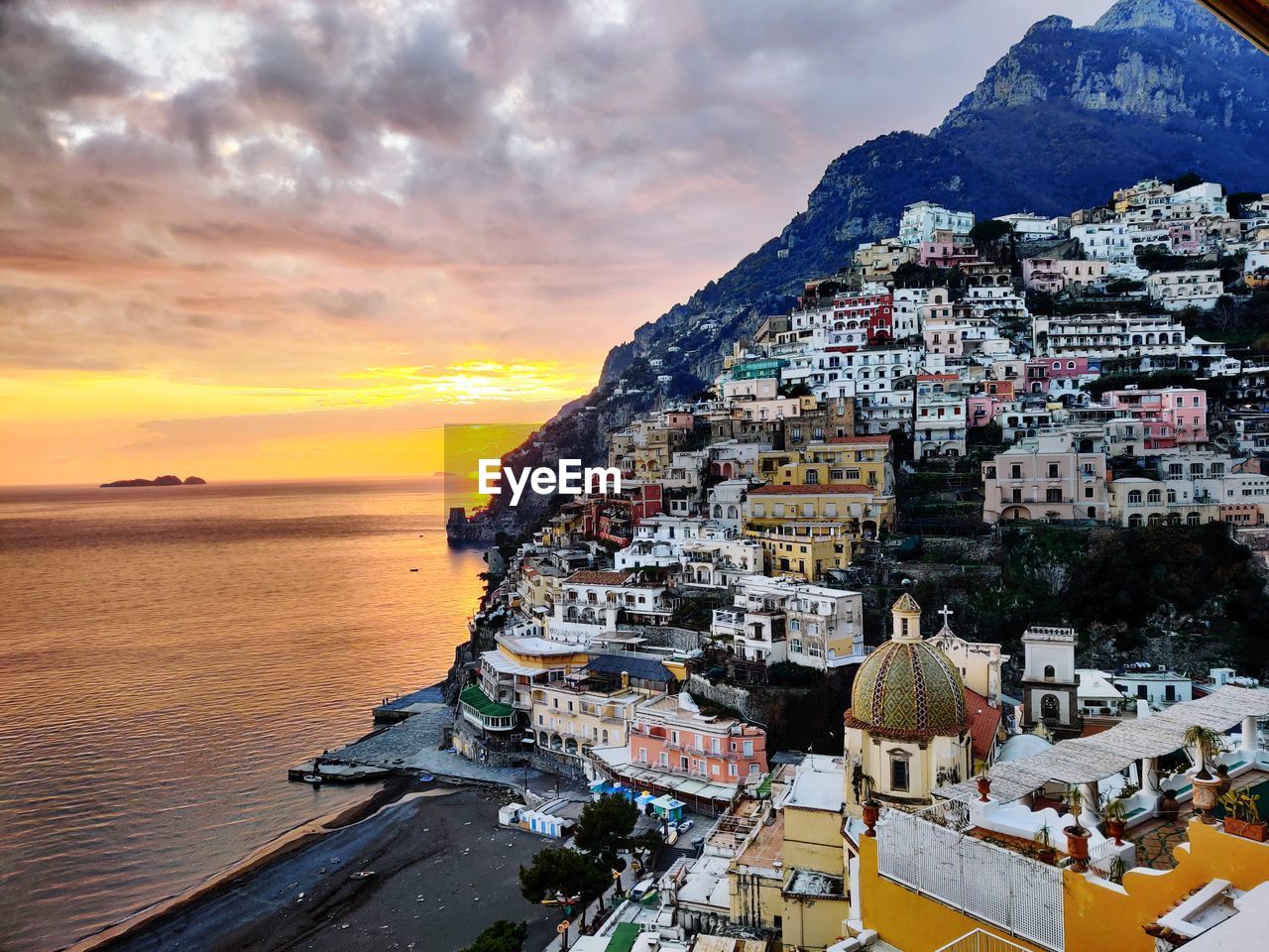 Panoramic view of positano and buildings against sky during sunset