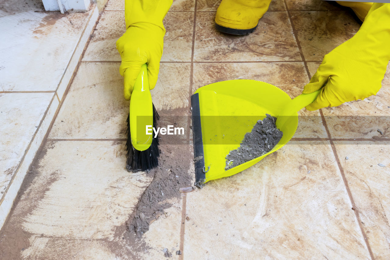 Person wearing gloves cleaning dust with duster at home