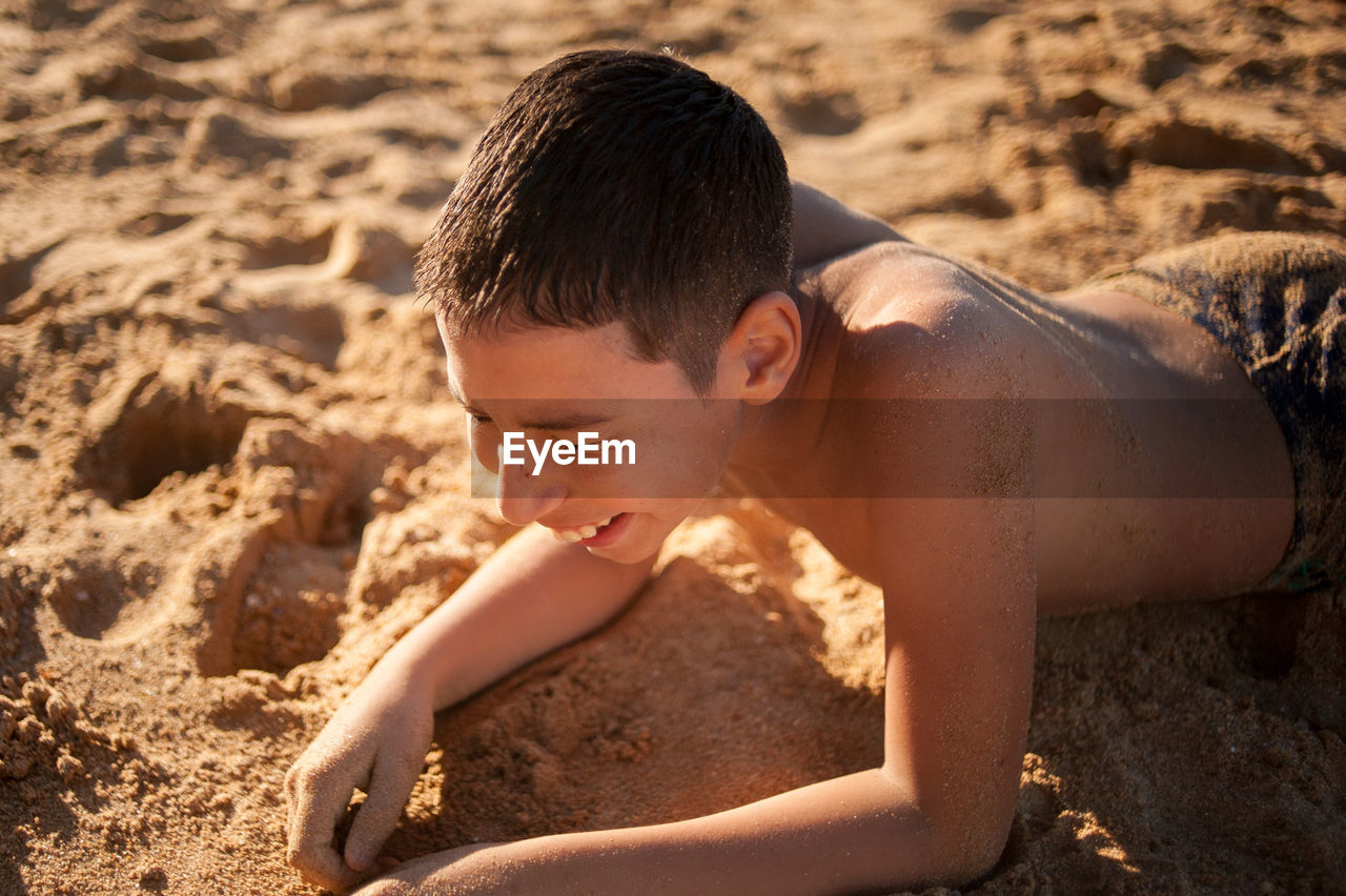 High angle view of shirtless boy on sand at beach
