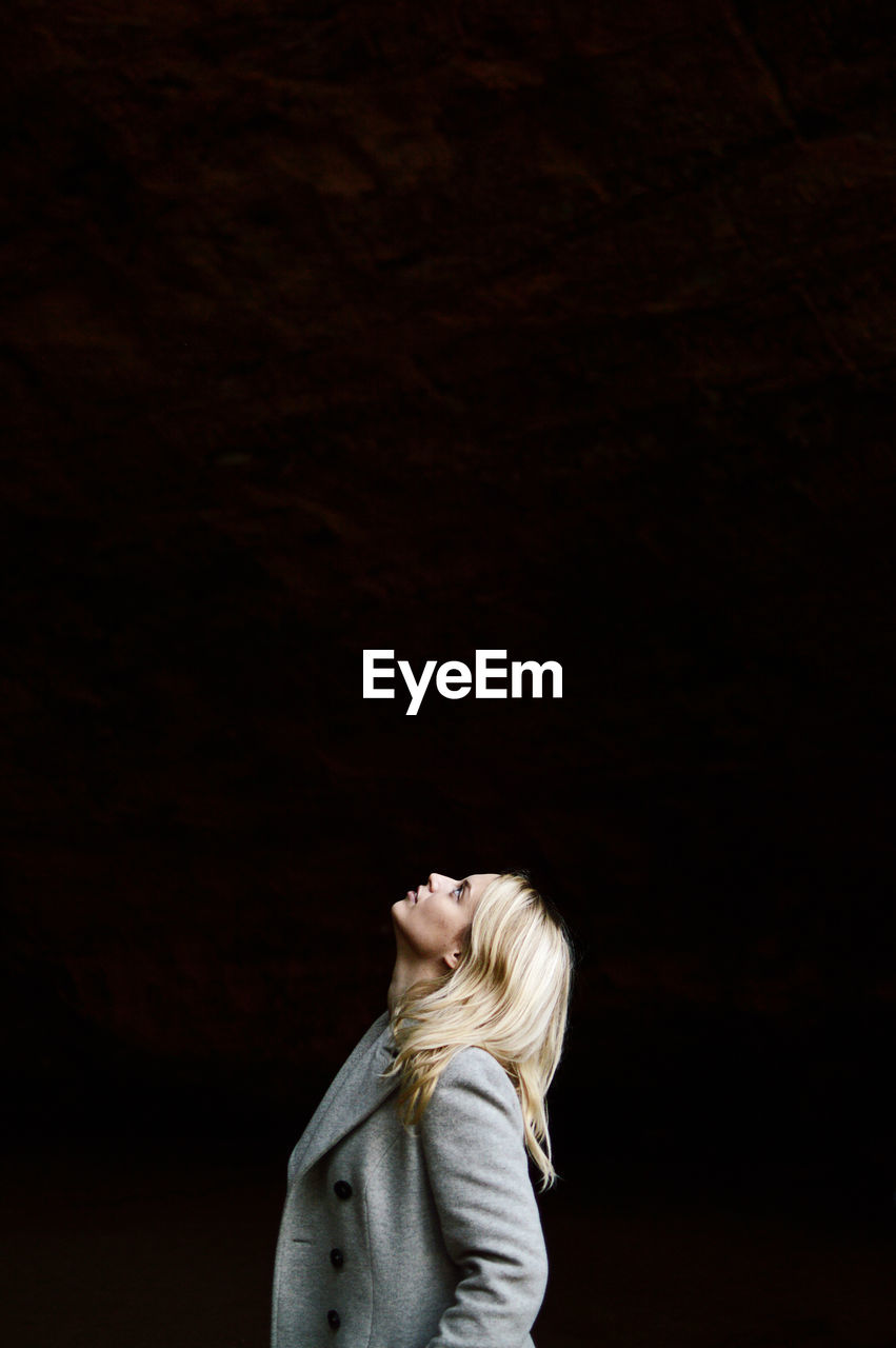 Woman looking up against black background