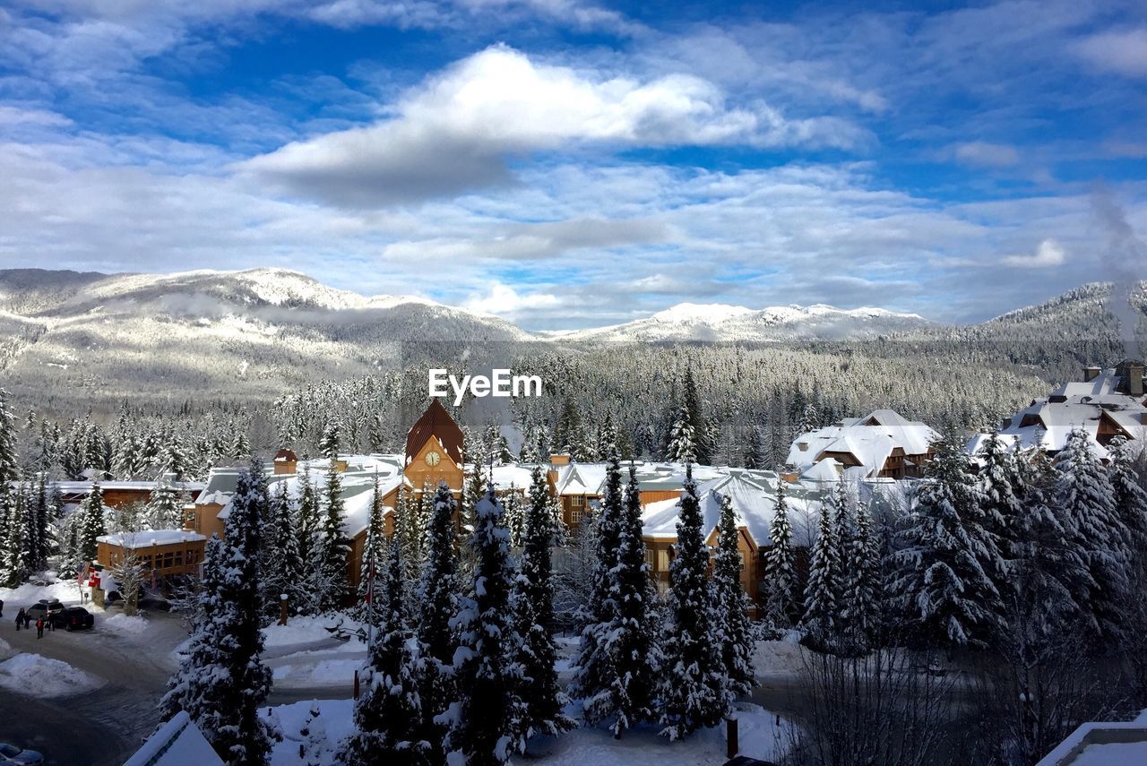 Snow covered houses by mountains against sky