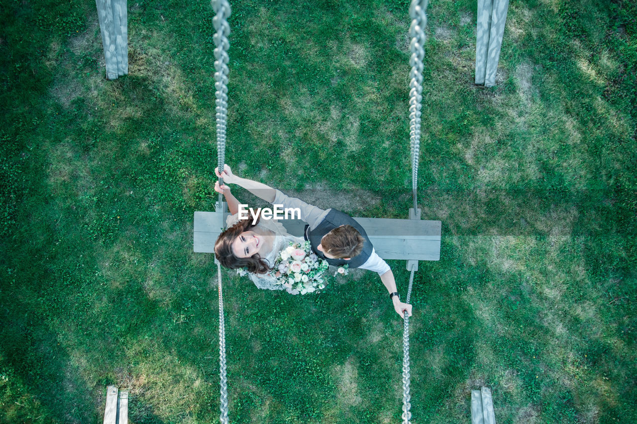 Bride and groom standing on swing at park