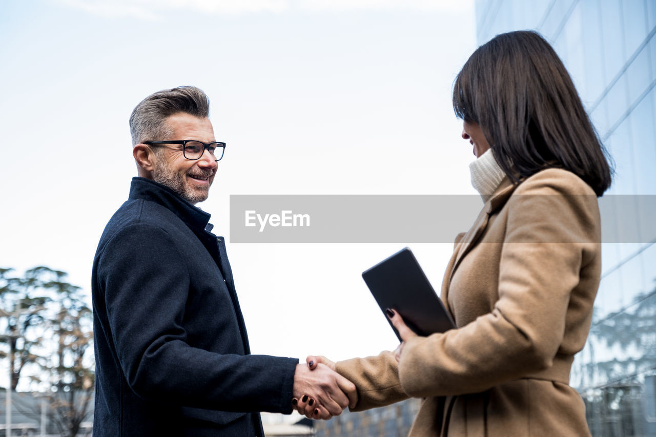 Smiling business people shaking hands outdoors