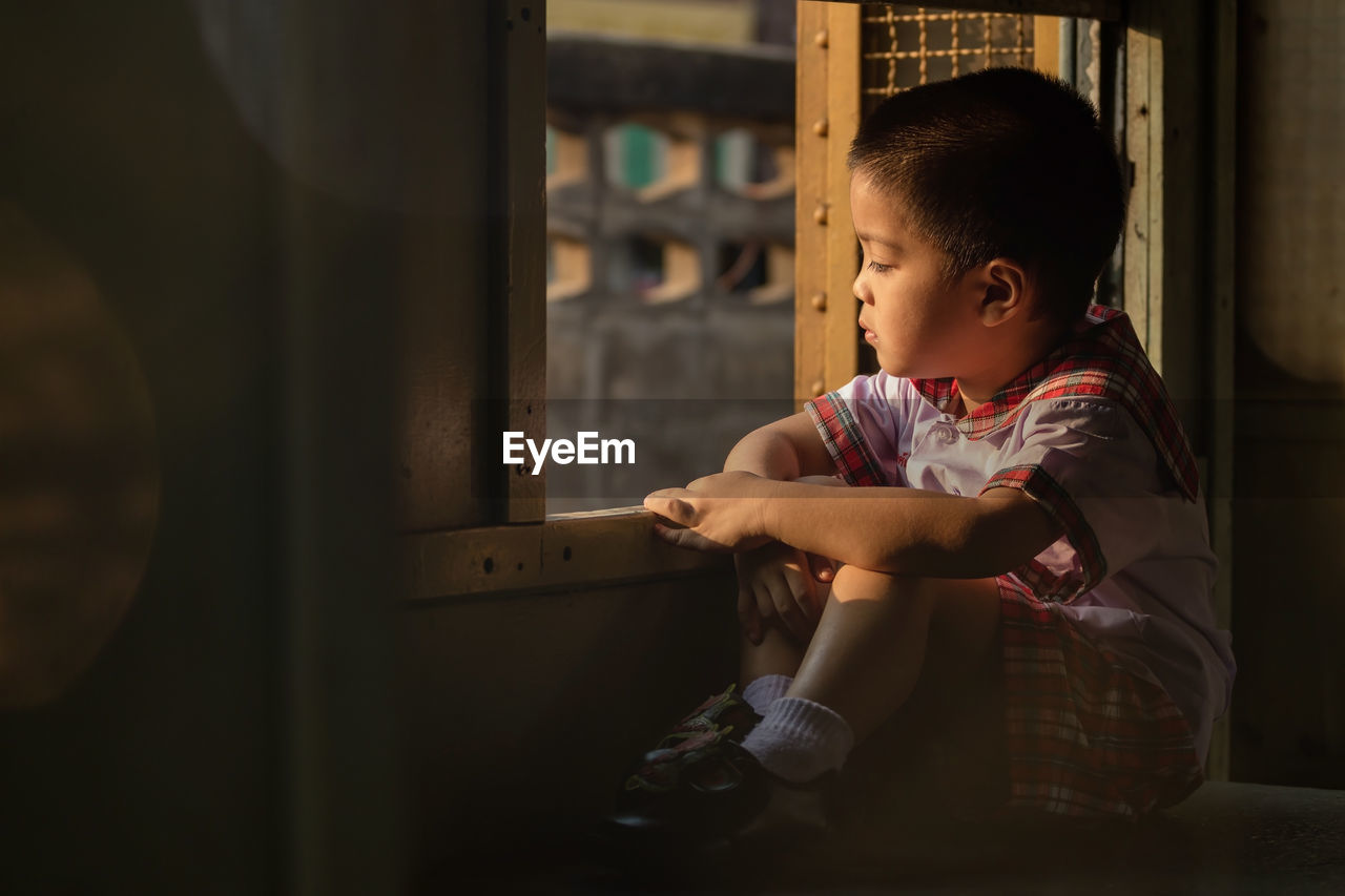 Boy looking through window at home