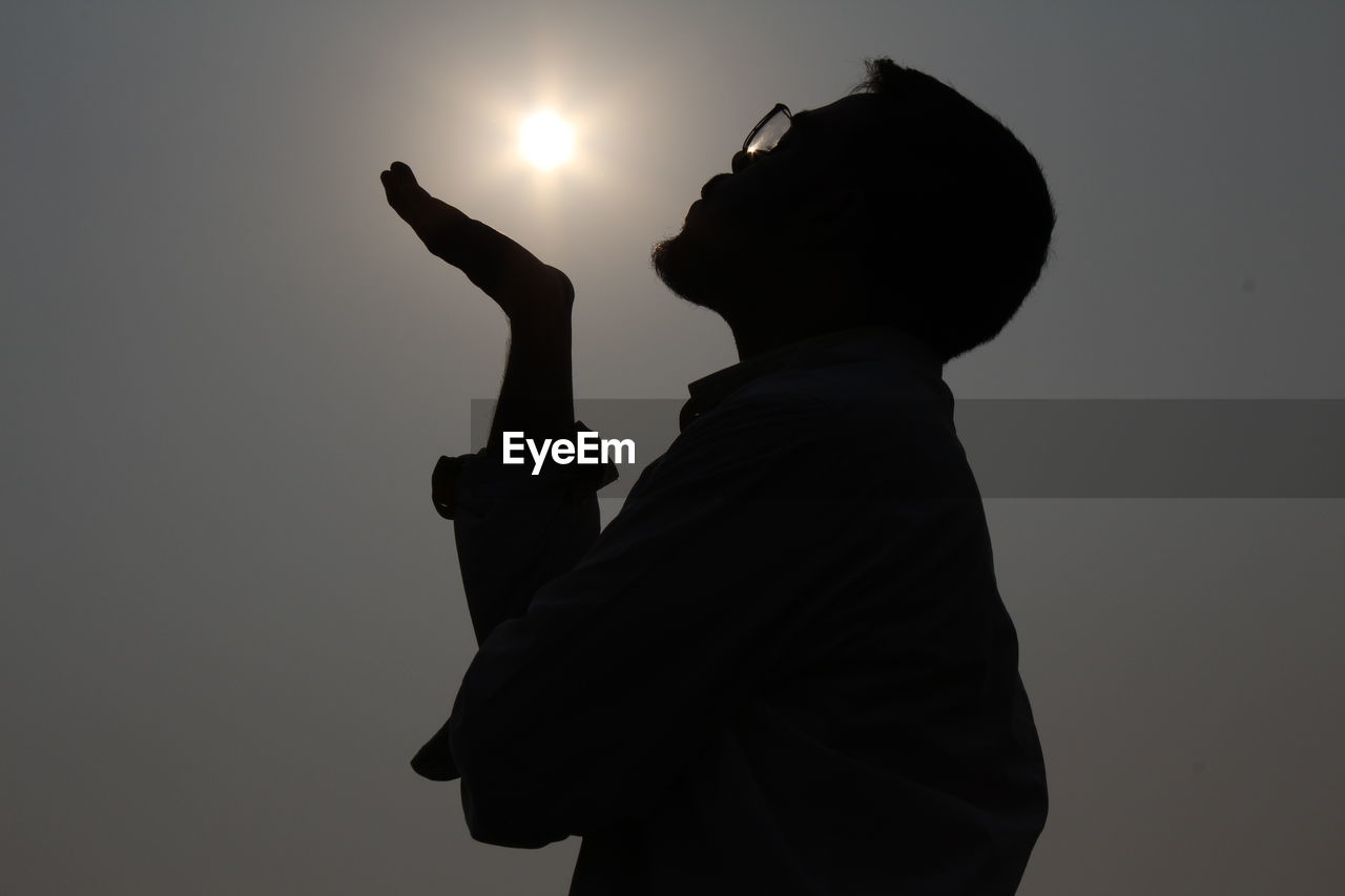 LOW ANGLE VIEW OF SILHOUETTE MAN AGAINST GRAY BACKGROUND