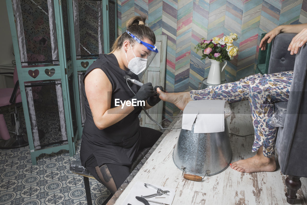 Beautician working with mask and protective screen for the virus covid