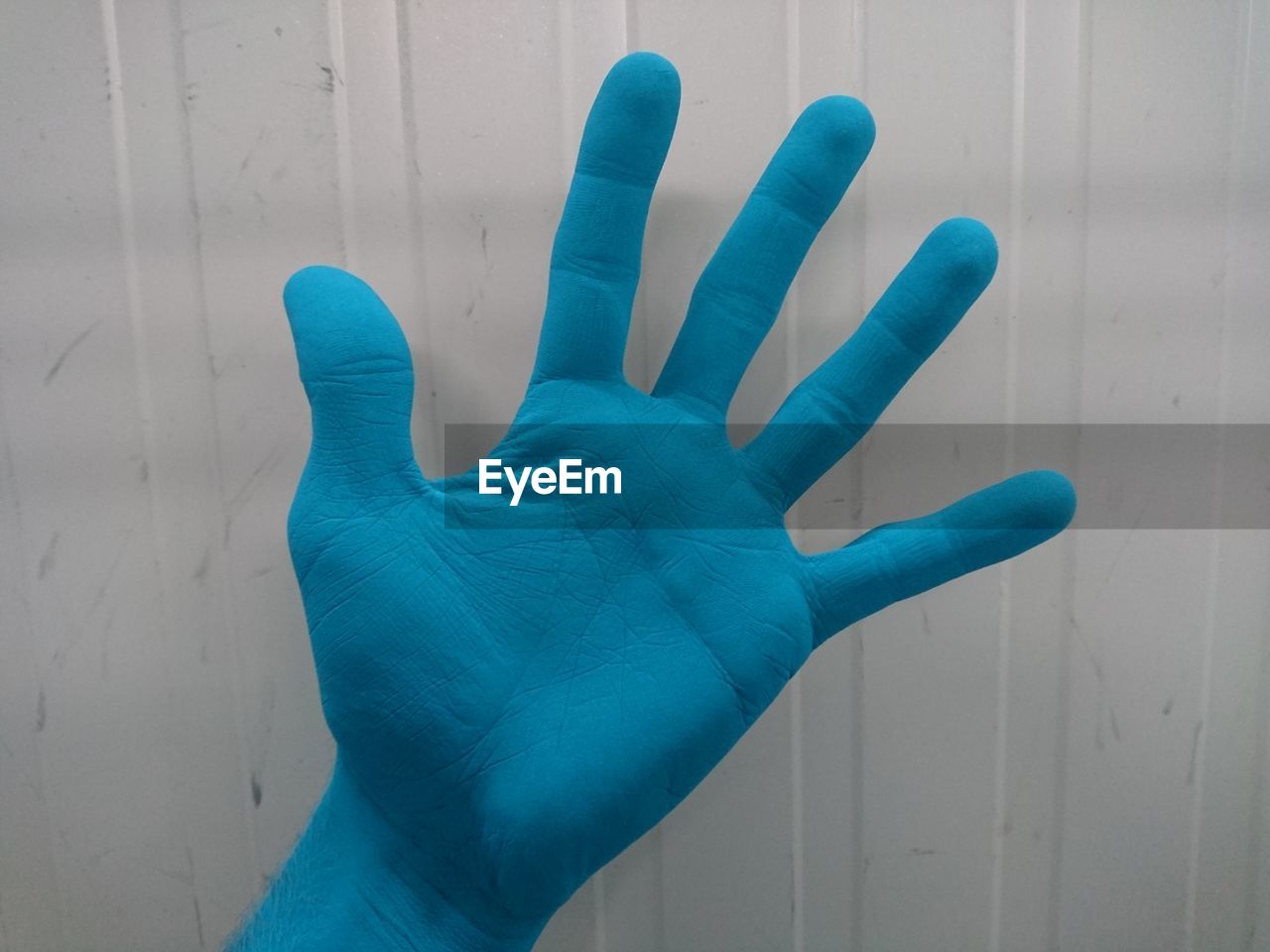 Cropped blue hand against wall