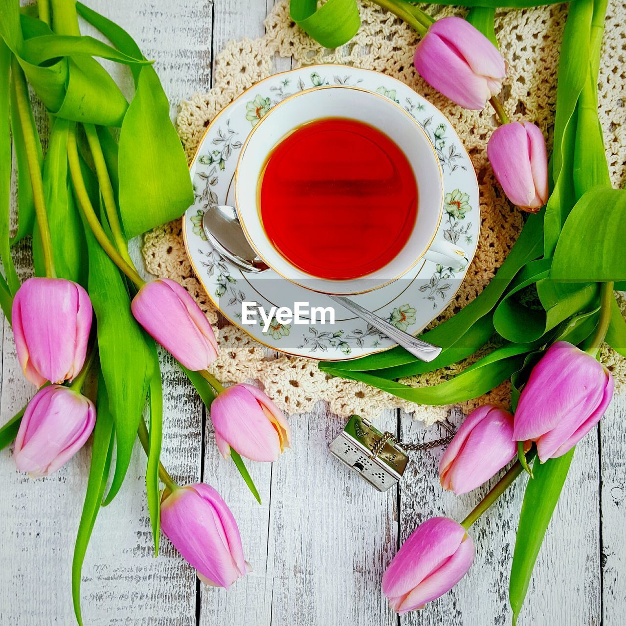 High angle view of tea cup with pink tulips on table