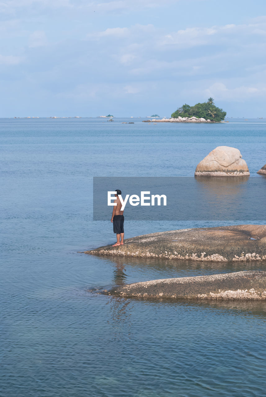 Man standing on rock in sea