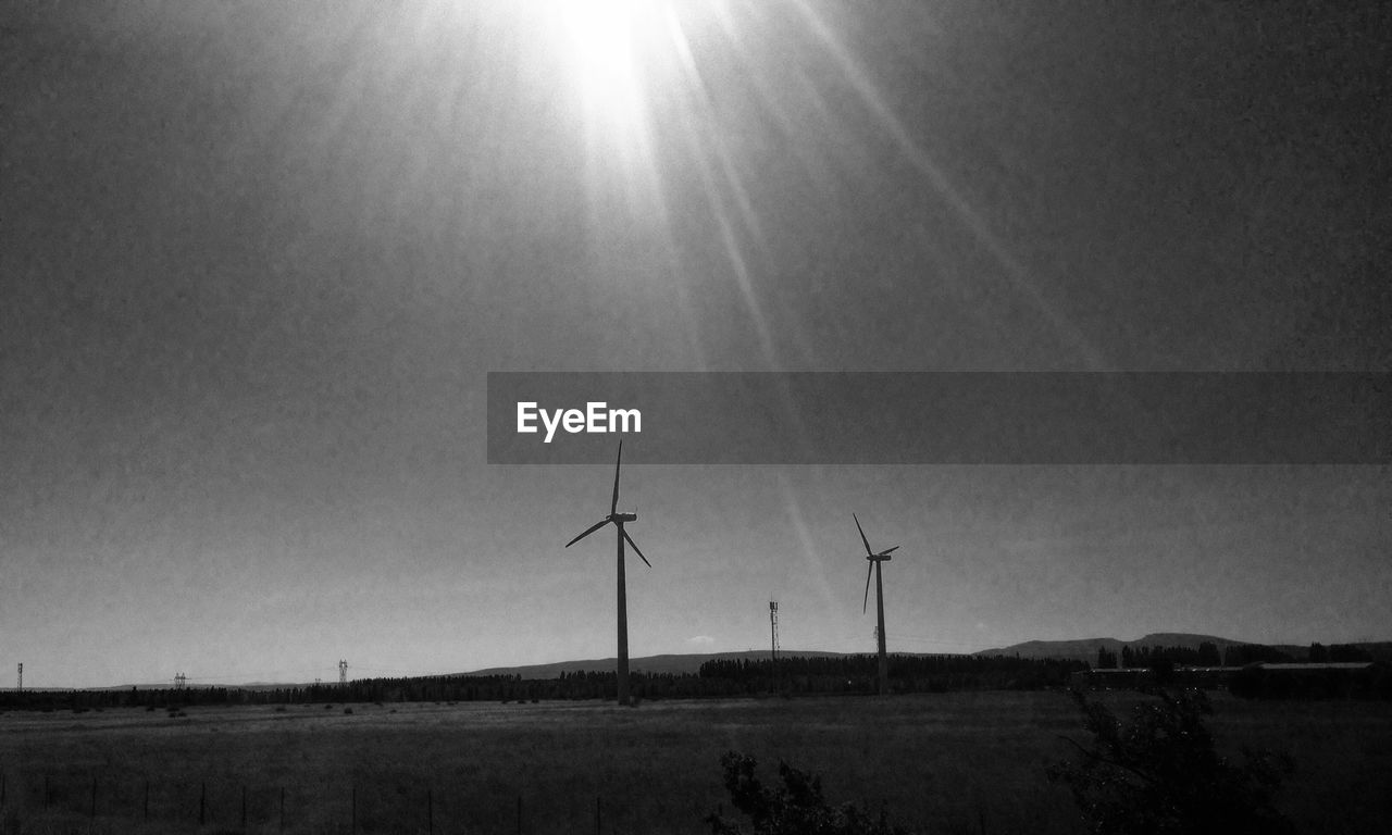 Silhouette windmills against sky