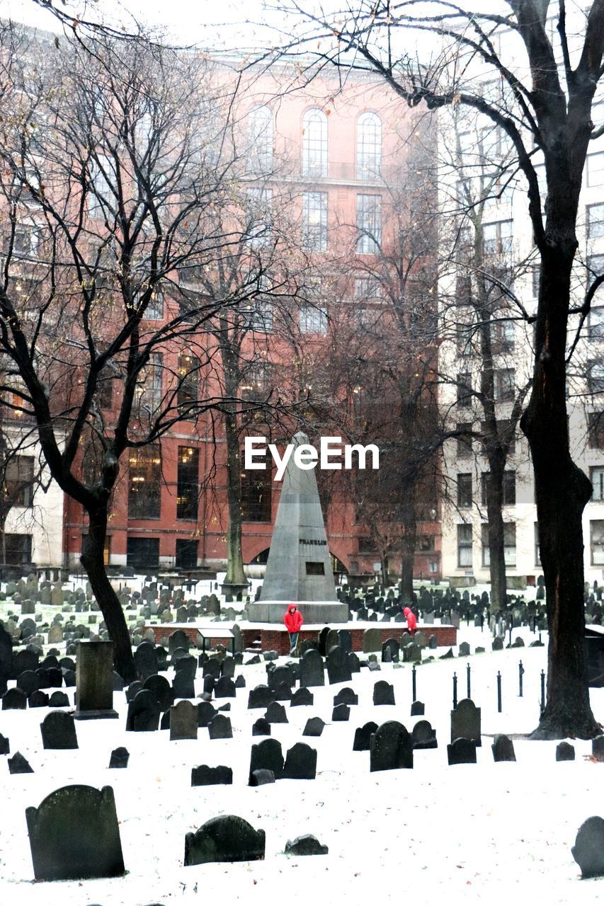 Tombstones and buildings at granary burying ground during snowfall