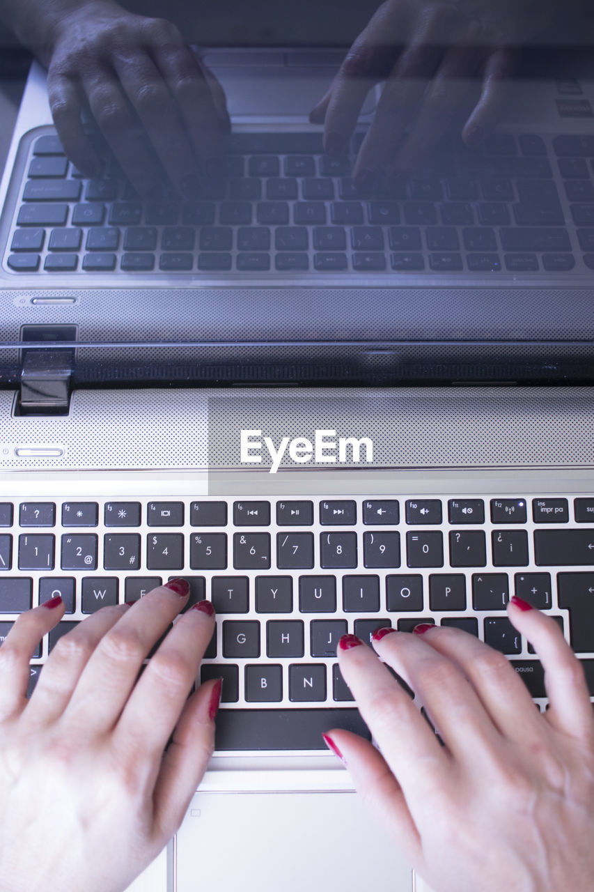 Cropped hands of woman using laptop