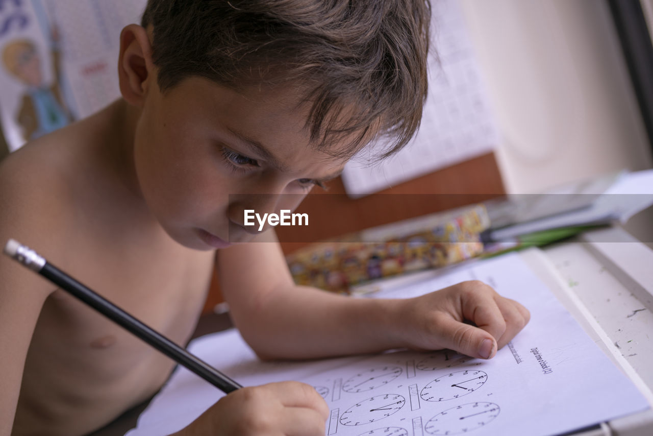 Shirtless boy drawing on paper